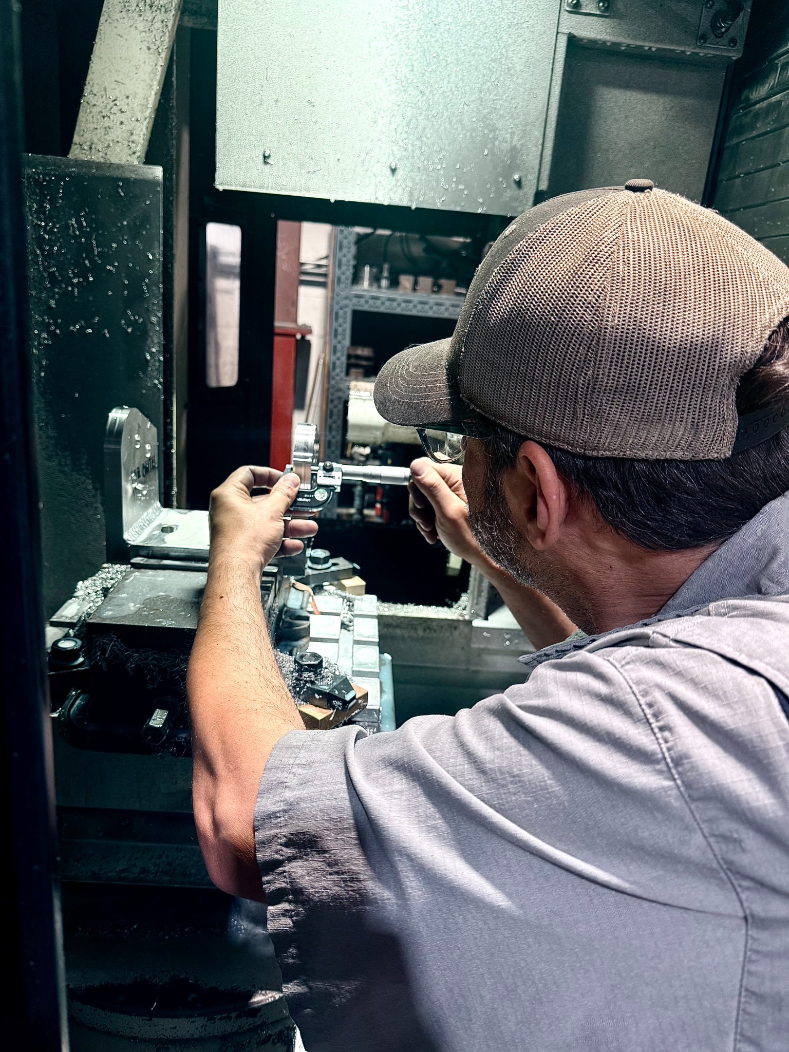 Machinist checking a part inside a CNC machine